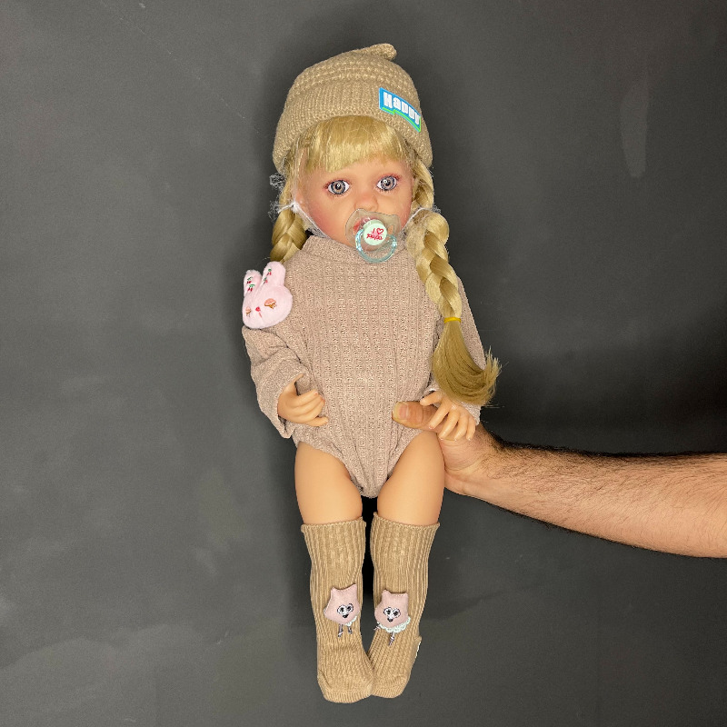 عروسک سیلیکونی وینیل واقعی ۲۲ اینچی(۵۵ سانتیمتر) با لباس کاموایی قهوه ای رنگ  و جوراب عروسکی و کلاه قهوه ای  به همراه لوازم جانبی برای سن +۳ Image