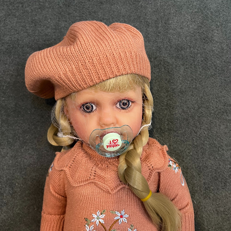 عروسک سیلیکونی وینیل واقعی ۲۲ اینچی(۵۵ سانتیمتر) با لباس کاموایی قهوه ای رنگ گل دار و کلاه به همراه لوازم جانبی برای سن +۳ Image